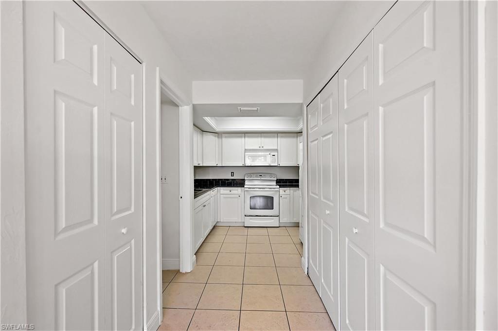 938 Augusta Boulevard, Unit D937 Naples, FL 34113 - Photo 18 of 27 a kitchen with white cabinets and white appliances