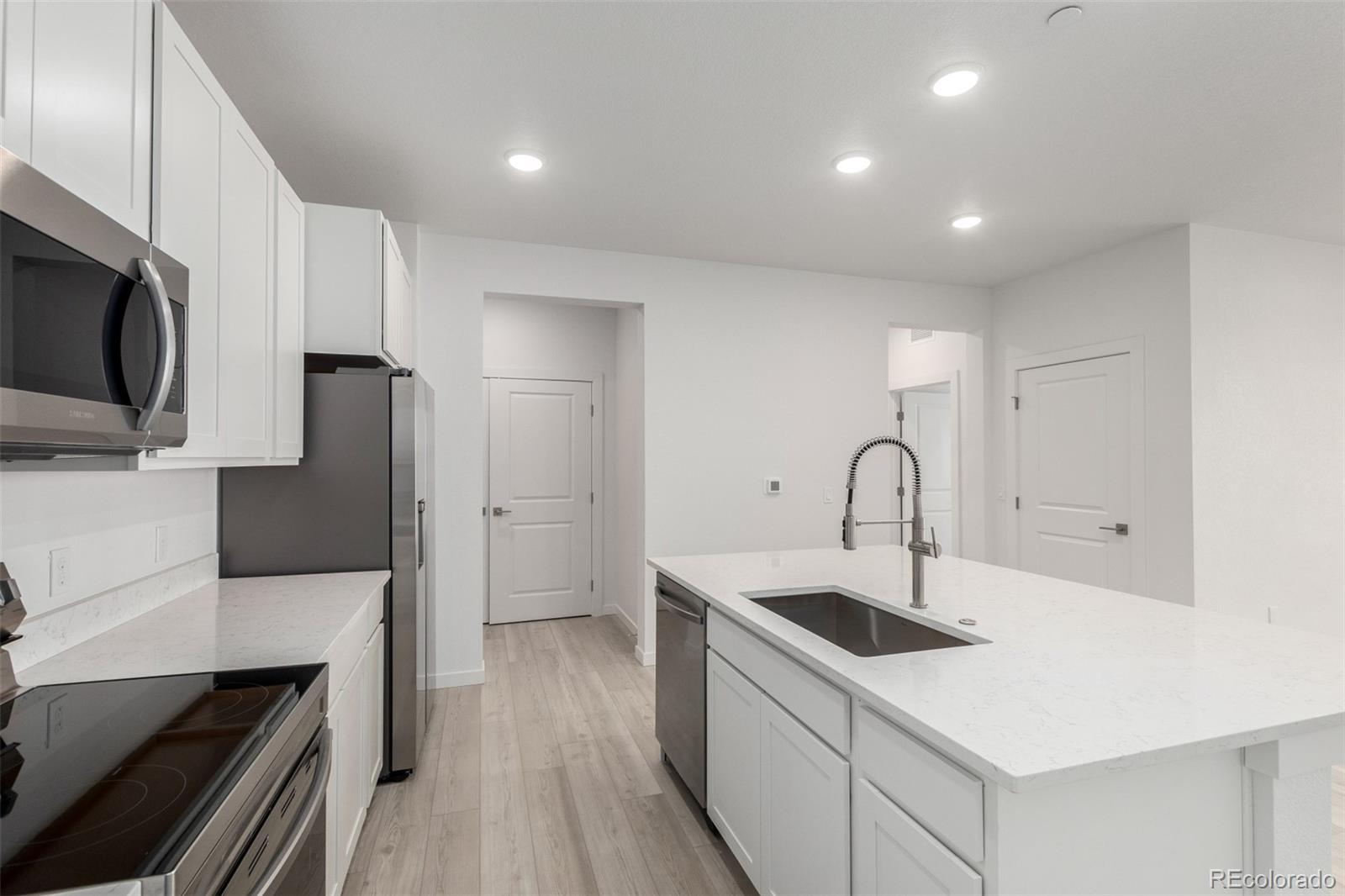 6153 North Ceylon Street, Unit 204 Denver, CO 80249 - Photo 5 of 22 a kitchen with stainless steel appliances a sink a stove top oven a counter space and cabinets