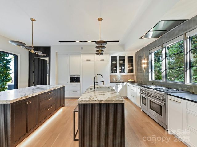a large kitchen with stainless steel appliances granite countertop a stove a sink and a wooden floors