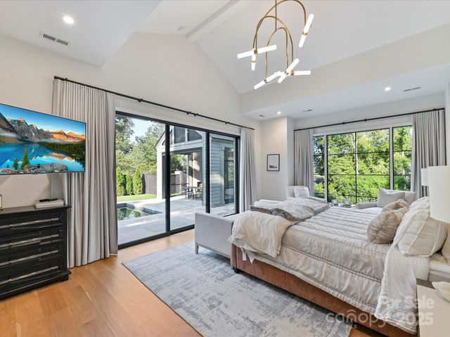 a spacious bedroom with a large bed and a chandelier