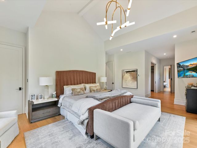 a spacious bedroom with a bed a chandelier and couch