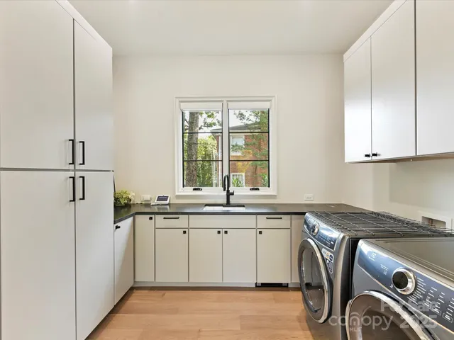 a utility room with stainless steel appliances granite countertop a sink and a window