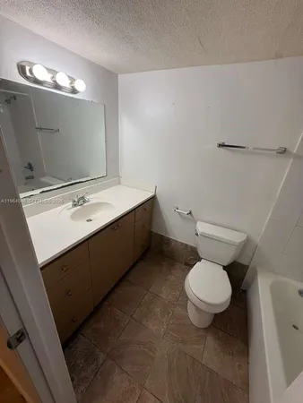a bathroom with a granite countertop sink toilet and mirror