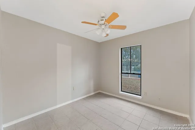 an empty room with window and ceiling fan