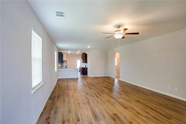 a view of an empty room with window and wooden floor