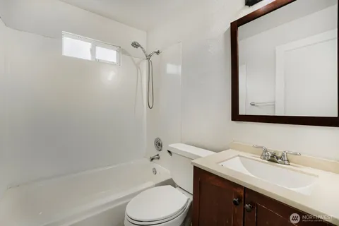 a bathroom with a toilet a sink a mirror a bathtub and vanity