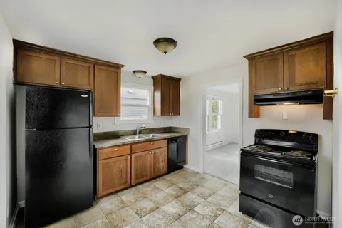 a kitchen with granite countertop a refrigerator a stove top oven a sink and dishwasher