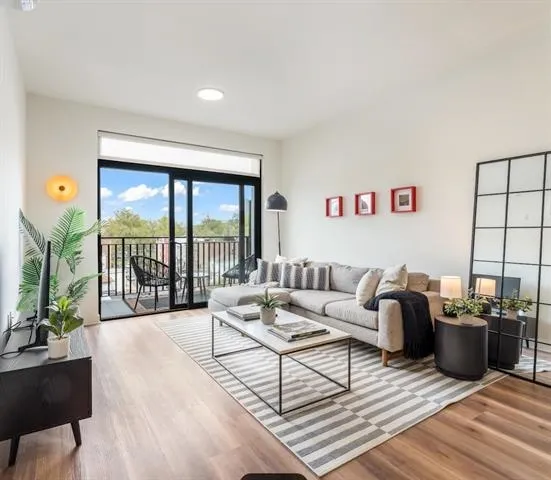 a living room with furniture a flat screen tv and a floor to ceiling window