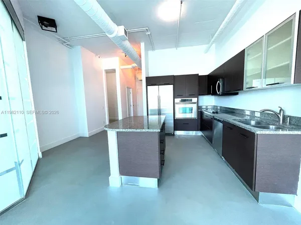 a large kitchen with stainless steel appliances granite countertop a refrigerator and a stove