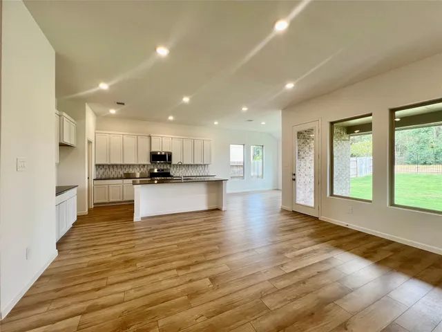 a view of kitchen with kitchen island granite countertop a stove top oven a sink and a refrigerator