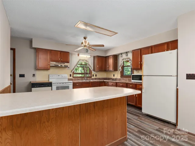 a kitchen with stainless steel appliances granite countertop a refrigerator a sink dishwasher a stove with wooden floors