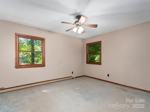 an empty room with windows and ceiling fan