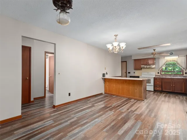 a kitchen with stainless steel appliances granite countertop a stove a sink dishwasher and a large mirror with wooden floor