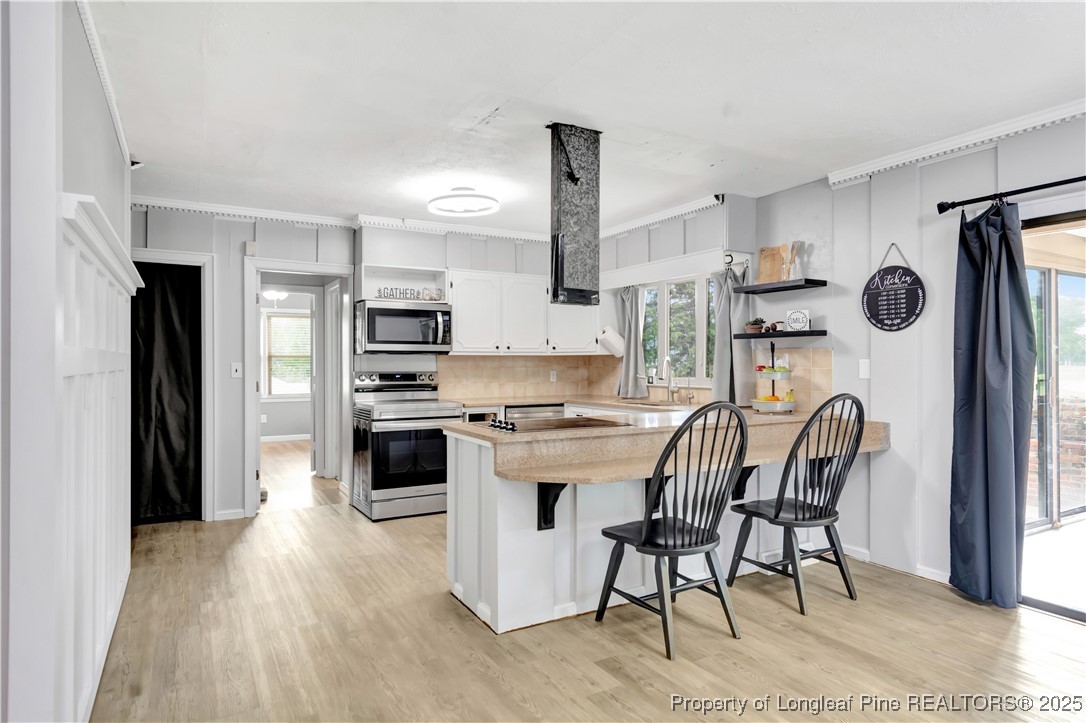 12073 Highway 130 Fairmont, NC 28340 - Photo 12 of 45 a kitchen with stainless steel appliances a stove a sink dishwasher a refrigerator white cabinets and wooden floor