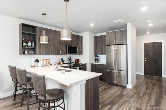 a kitchen with stainless steel appliances kitchen island granite countertop a sink refrigerator and cabinets