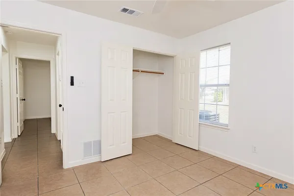 a view of an empty room with closet and a window