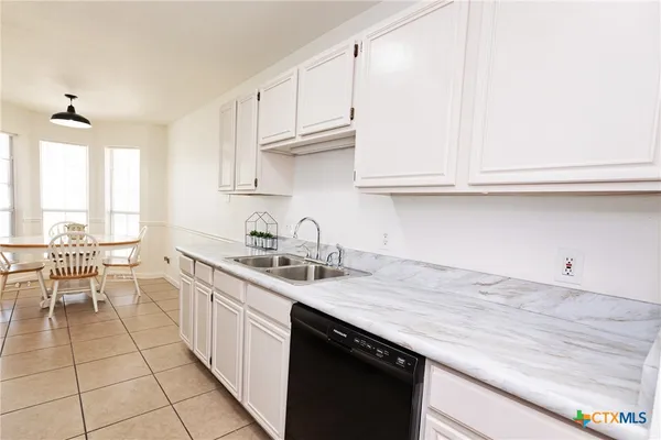 a kitchen with a sink dishwasher a stove and white cabinets with wooden floor