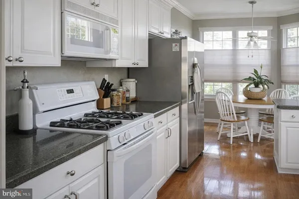 a kitchen with granite countertop a stove a refrigerator and wooden floor