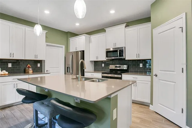 a kitchen with kitchen island a appliances a sink and cabinets