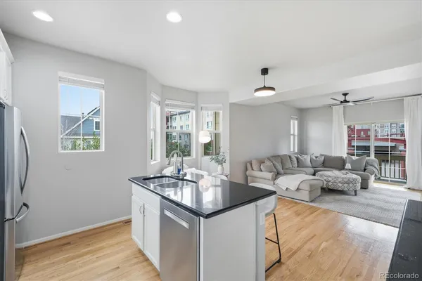 a living room with stainless steel appliances granite countertop furniture and a wooden floor