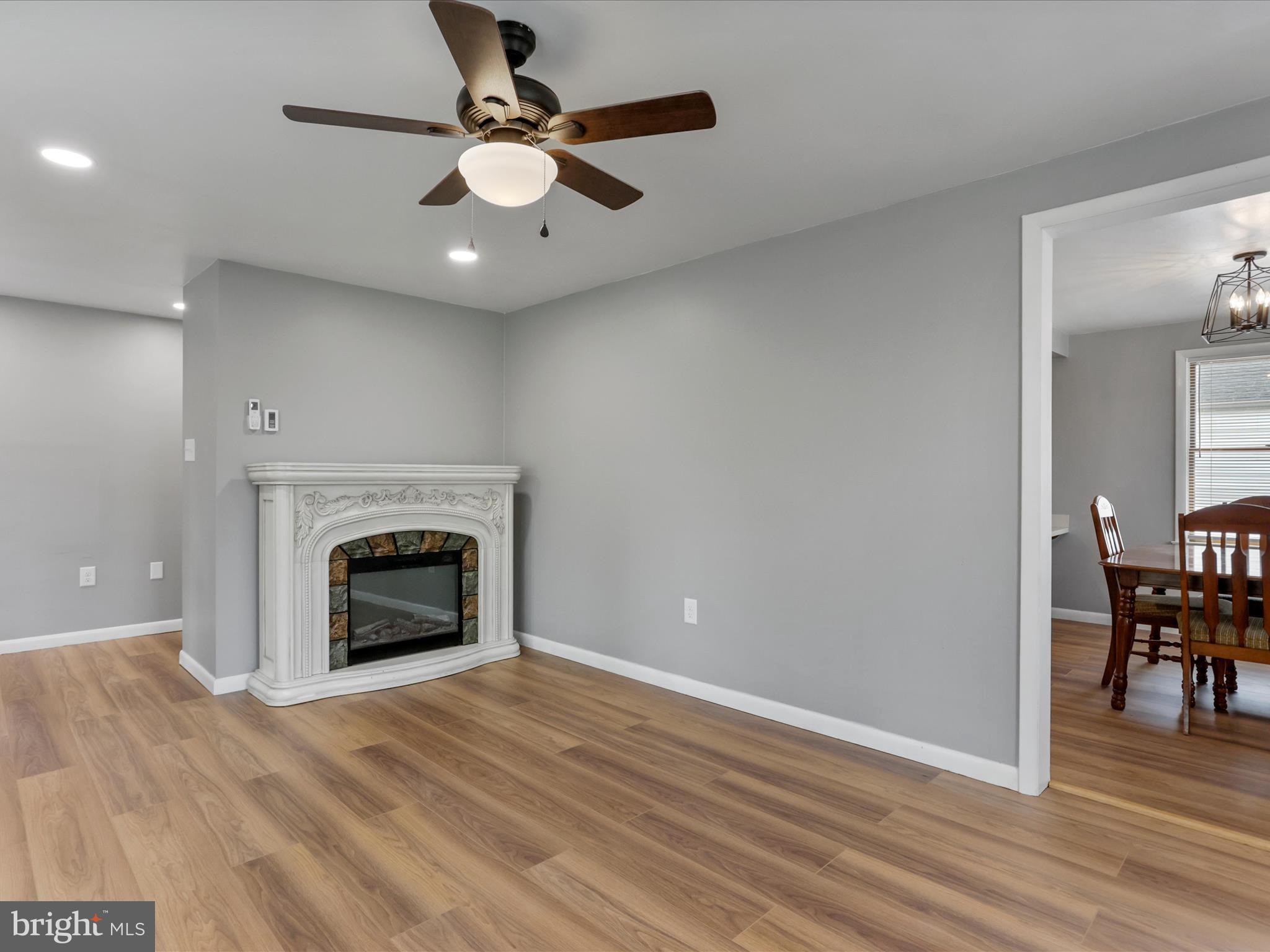 12343 Big Spring Road Clear Spring, MD 21722 - Photo 19 of 34 an empty room with wooden floor a ceiling fan a fireplace and windows