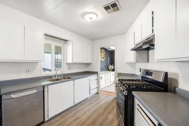 a kitchen with stainless steel appliances a sink stove and cabinets