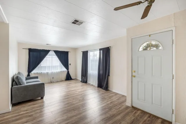 a view of an empty room with wooden floor and a window
