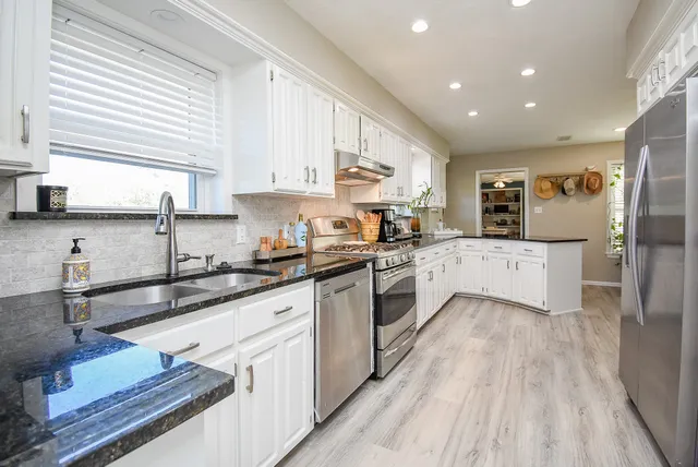 a large kitchen with stainless steel appliances granite countertop a lot of counter space and wooden floors