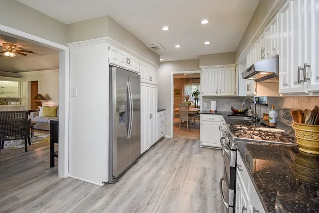 a kitchen with stainless steel appliances granite countertop a refrigerator stove top oven and sink