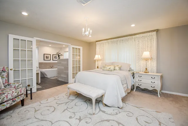 a spacious bedroom with a bed a table and chair