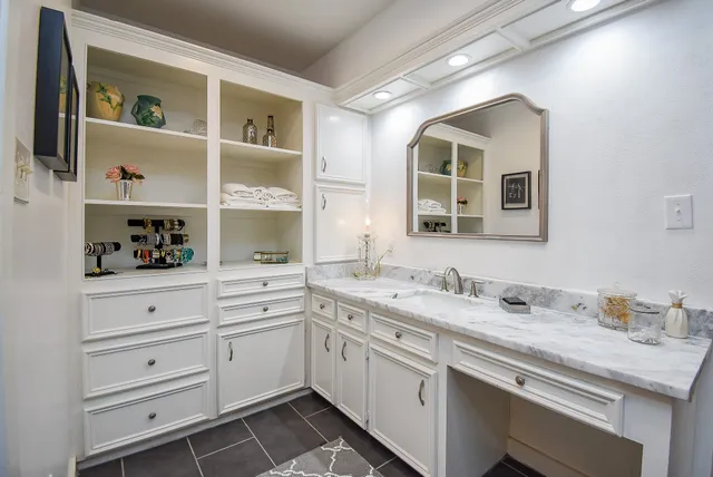 a white kitchen with a sink and dishwasher with white cabinets