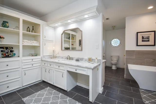 a spacious bathroom with a double vanity sink a mirror and a toilet