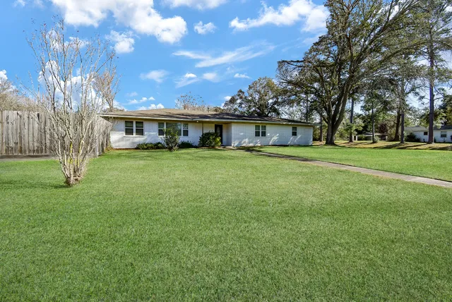 a view of a house with a big yard and large trees
