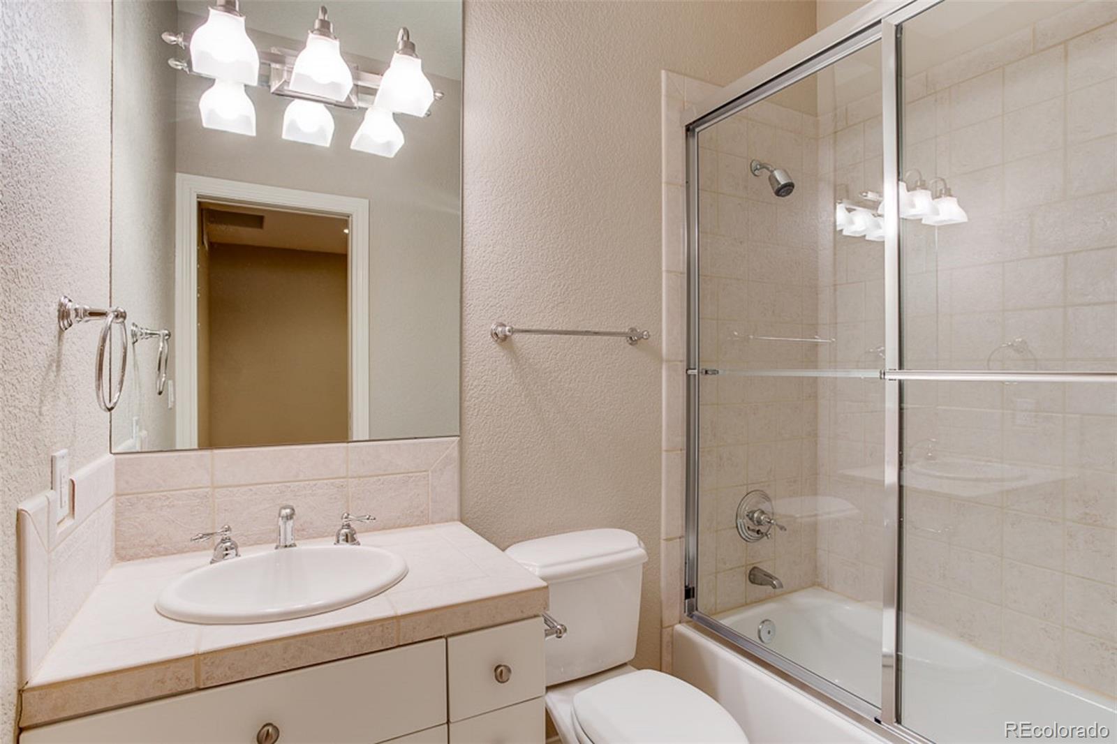 338 St Paul Street Denver, CO 80206 - Photo 30 of 35 a bathroom with a granite countertop sink toilet a mirror and shower