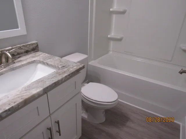 a bathroom with a granite countertop toilet sink and mirror