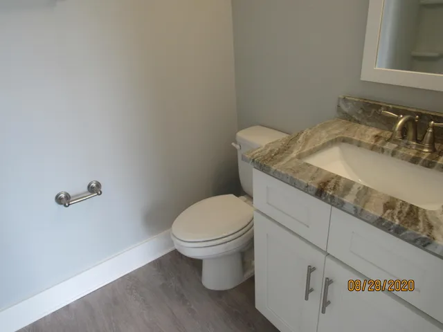 a bathroom with a granite countertop toilet and a sink
