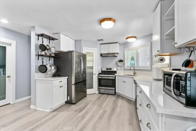 a kitchen with stainless steel appliances a stove a refrigerator a sink a counter space and cabinets