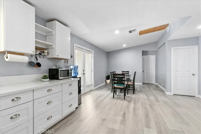 a kitchen with white cabinets and wooden floors