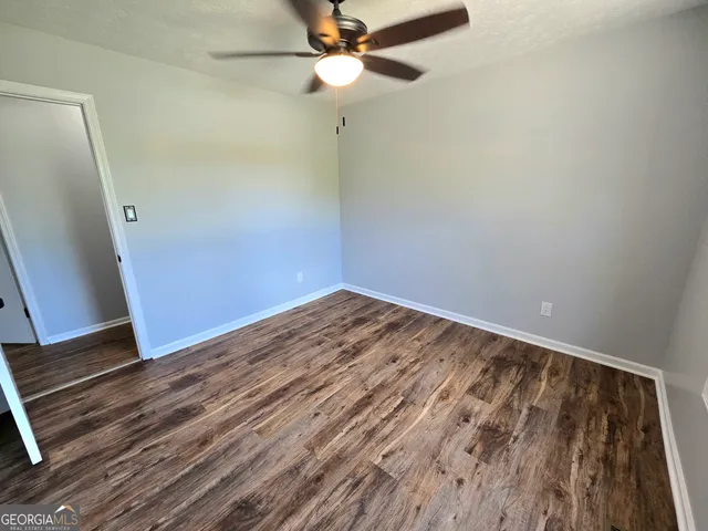 an empty room with wooden floor fan and windows