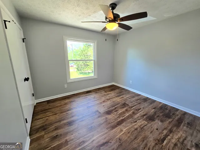 an empty room with wooden floor fan and windows