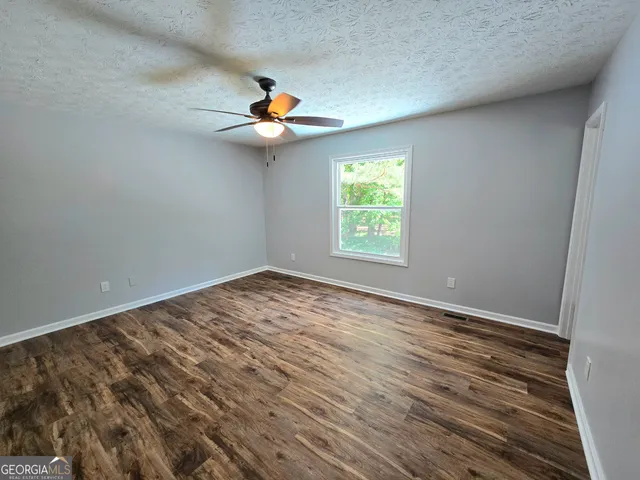 an empty room with windows and fan