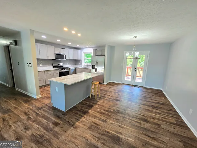 a large kitchen with kitchen island a sink wooden floor and stainless steel appliances