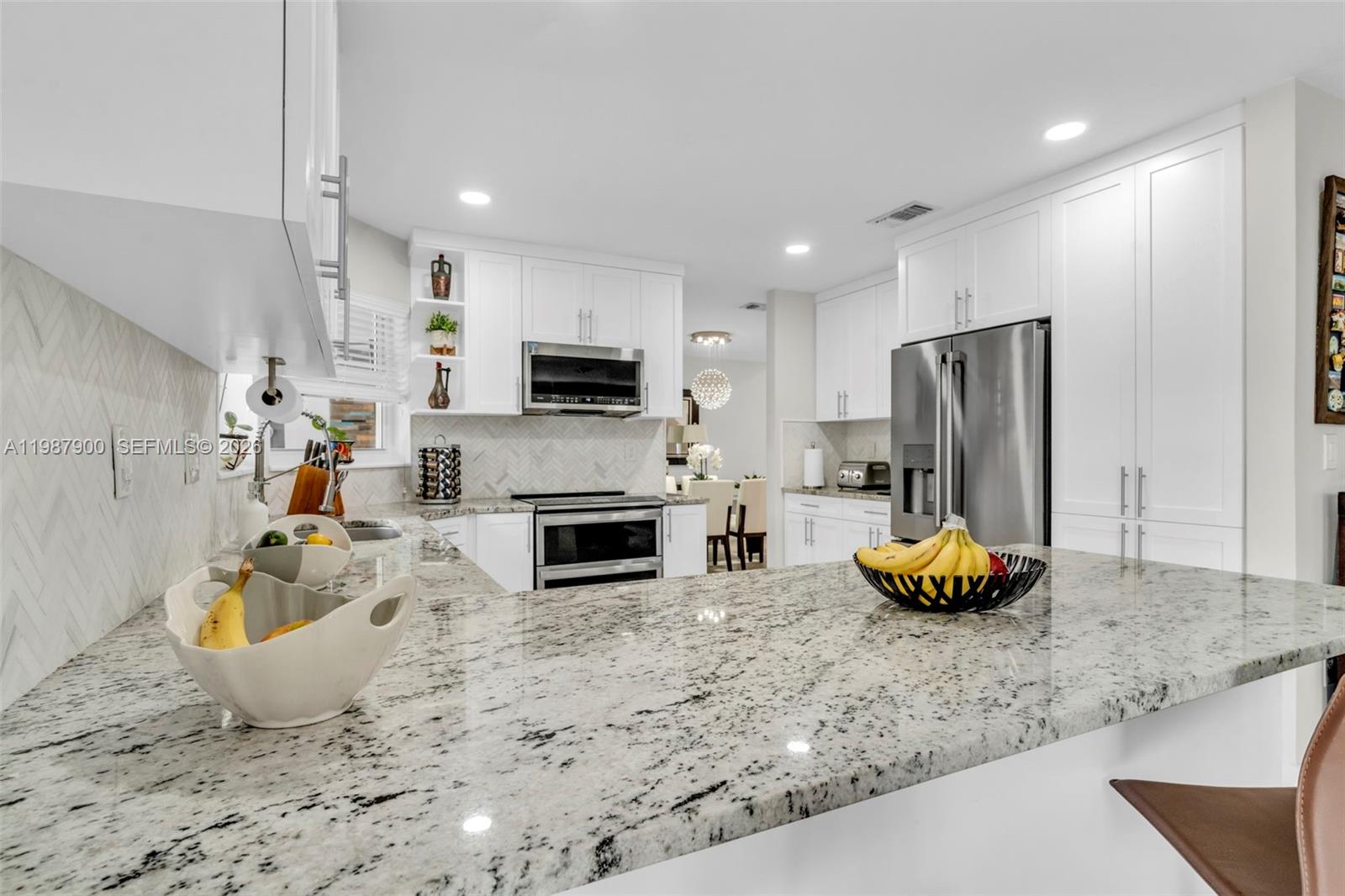 15726 Southwest 76th Terrace Miami, FL 33193 - Photo 12 of 34 a kitchen with a sink a microwave a refrigerator and white cabinets
