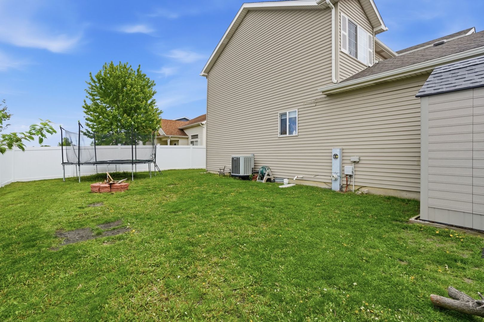 797 Kyle Court Braidwood, IL 60408 - Photo 24 of 33 a backyard of a white house with potted plants and a large tree