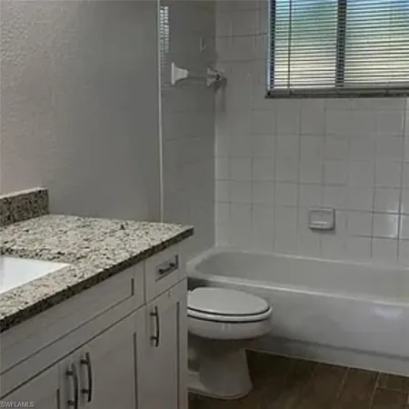 a bathroom with a granite countertop toilet a sink and bathtub