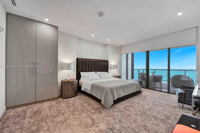 a bedroom with a bed a table and chair with the large mirror