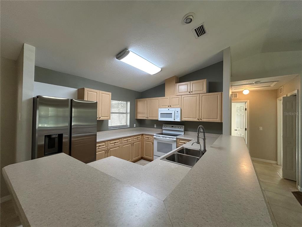3764 East Sanders Street Inverness, FL 34453 - Photo 14 of 39 a kitchen with stainless steel appliances kitchen island granite countertop a sink refrigerator and cabinets