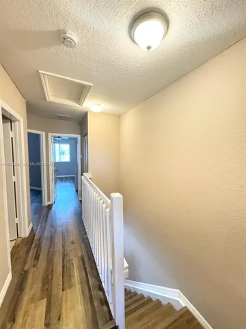 a view of a hallway with wooden floor and staircase