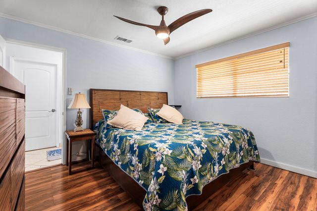 a bedroom with a bed a dresser and wooden floor