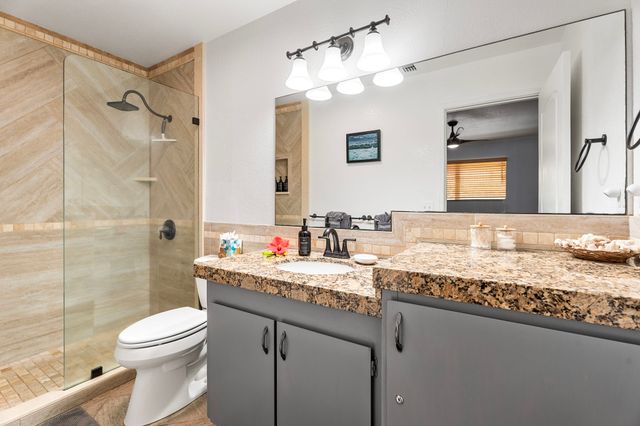 a bathroom with a granite countertop sink toilet a mirror a vanity and shower